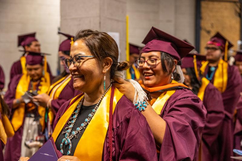 Sun Devil graduates fix their regalia before walking the stage at the American Indian Convocation